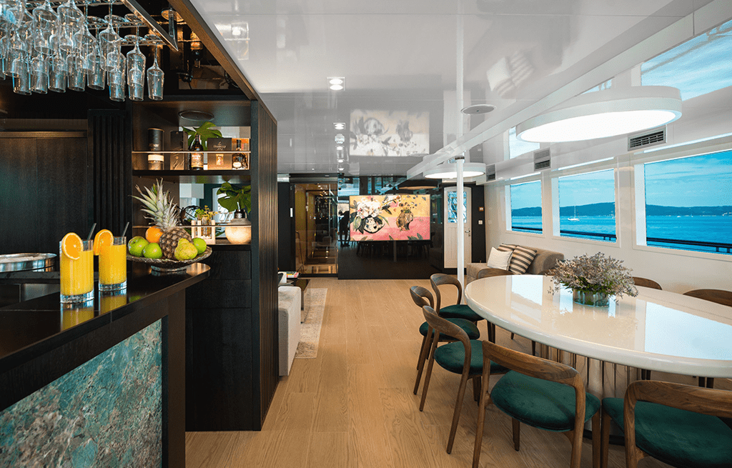 Modern yacht salon featuring dining table, bar area and panoramic ocean windows
