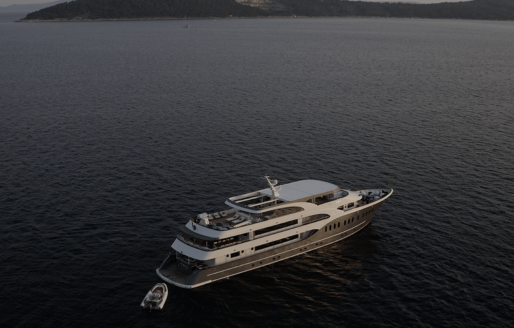 aerial view luxury motor yacht anchored dark waters with small tender boat