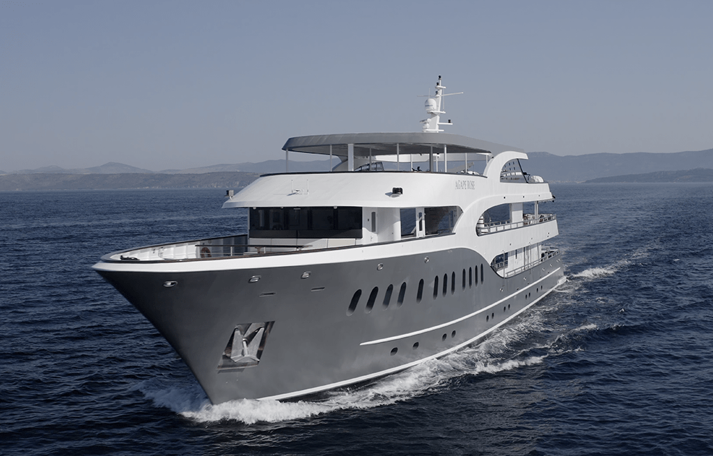 Grey hull motor yacht with white superstructure cruising on blue water