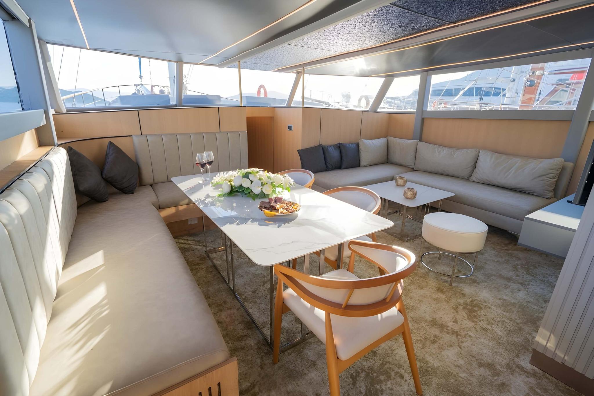 yacht salon interior with L-shaped seating, dining table, and panoramic windows
