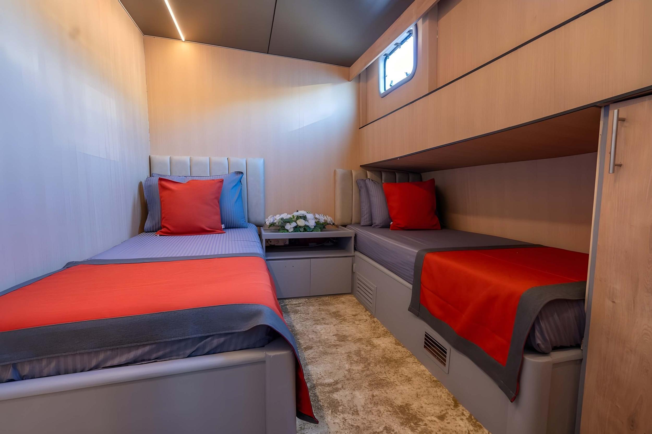twin cabin with two single beds featuring red and grey bedding and built-in storage