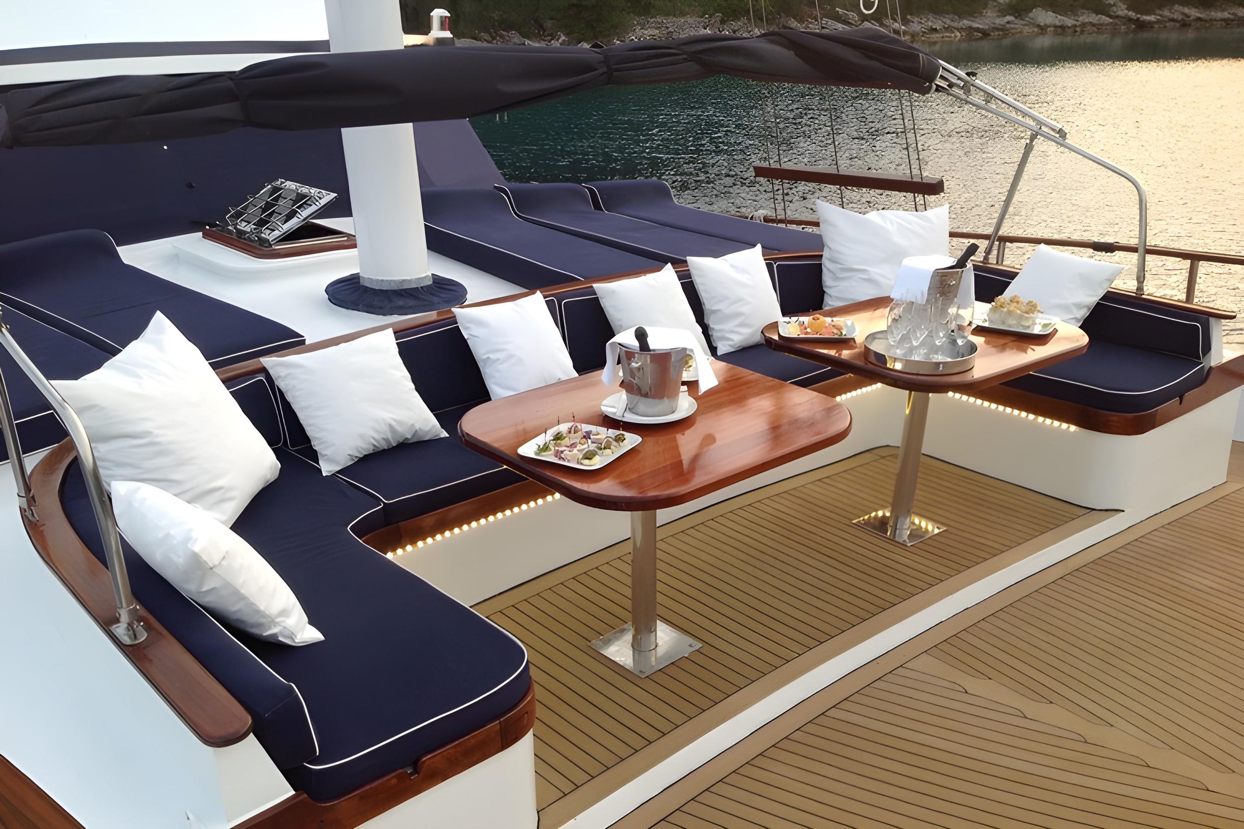 yacht aft deck with navy blue seating, teak dining table, and white cushions