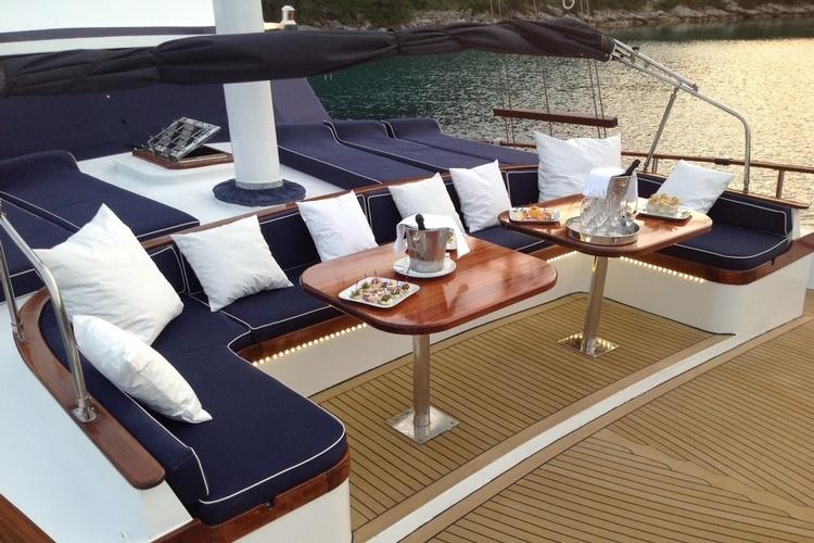 yacht aft deck with navy blue seating, teak dining table, and white cushions