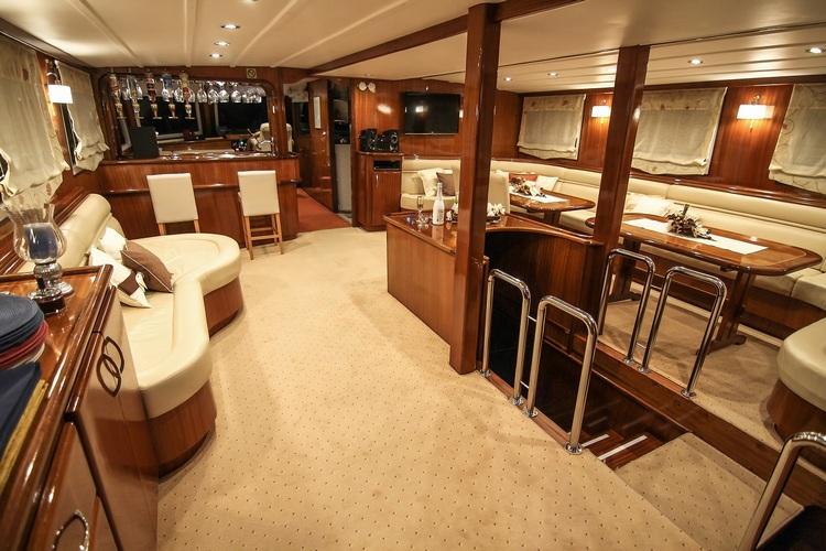 luxury yacht main salon with cream leather seating, wooden bar area and dining space