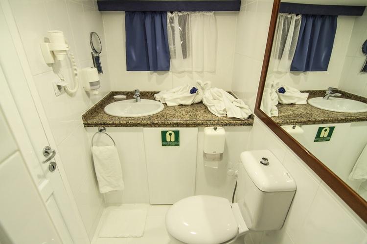 yacht bathroom featuring granite countertop vanity, oval sink, large mirror and white toilet