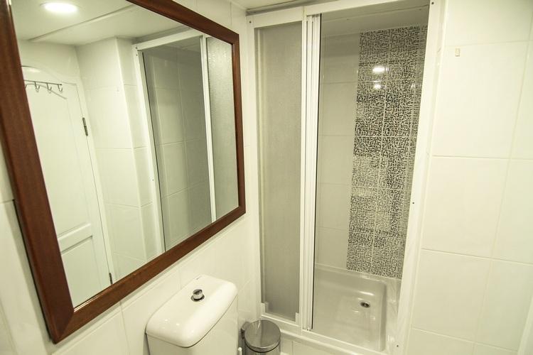 compact yacht bathroom featuring glass shower cubicle, wooden framed mirror and white fixtures