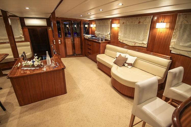 luxury yacht main salon with curved cream leather sofa, wood paneling and wet bar