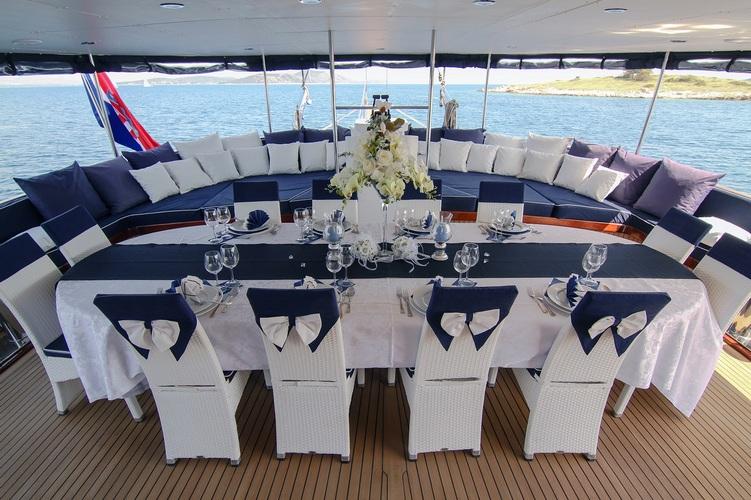 yacht aft deck with formal dining table, white chairs, and curved seating area