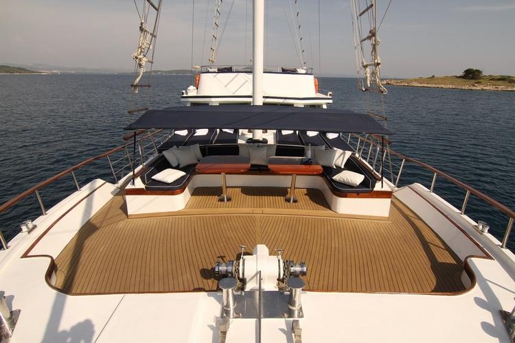 yacht upper deck with curved seating arrangement, teak decking and white mast