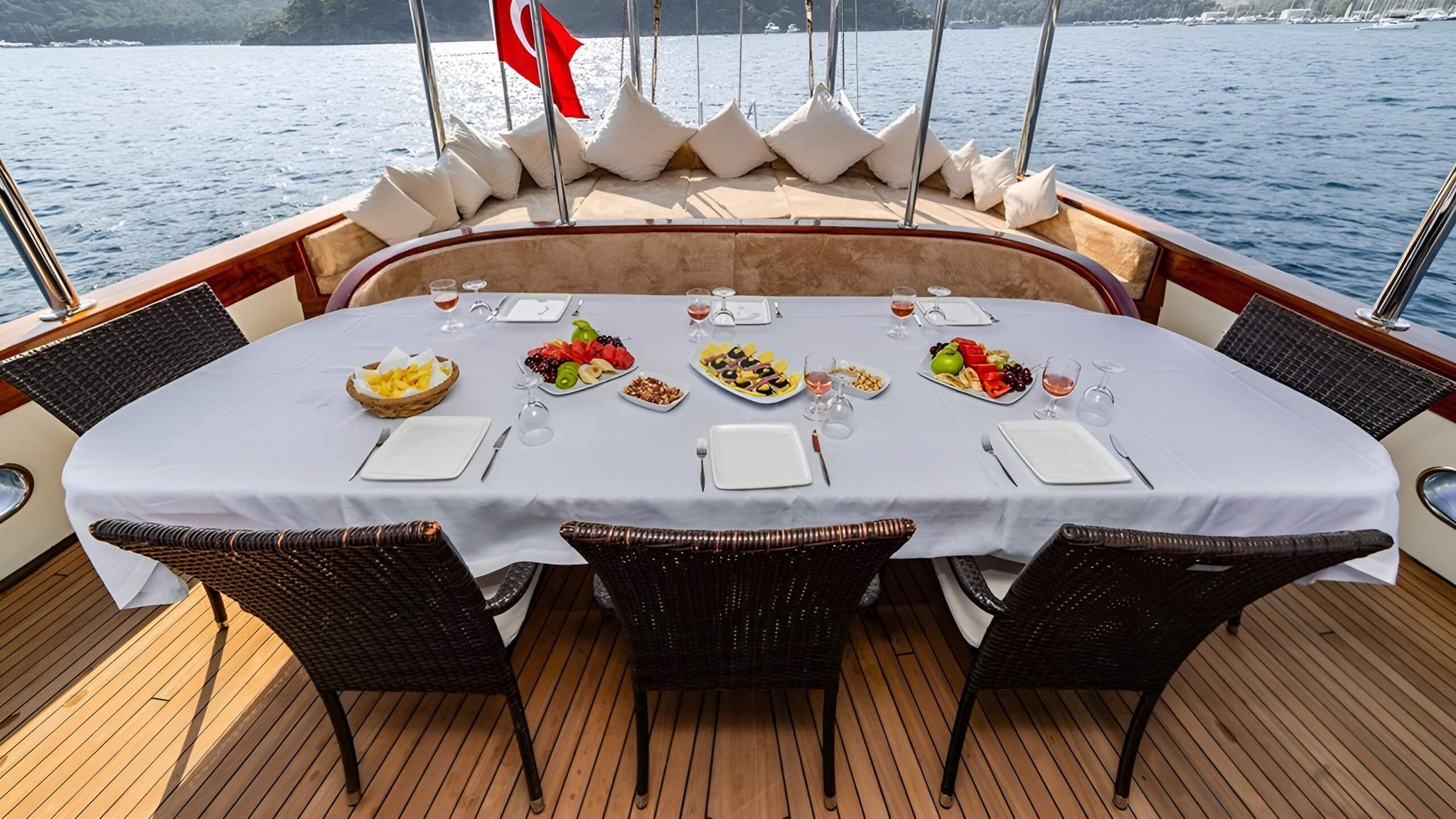 yacht aft deck dining table set with fresh fruit platters wine glasses and place settings