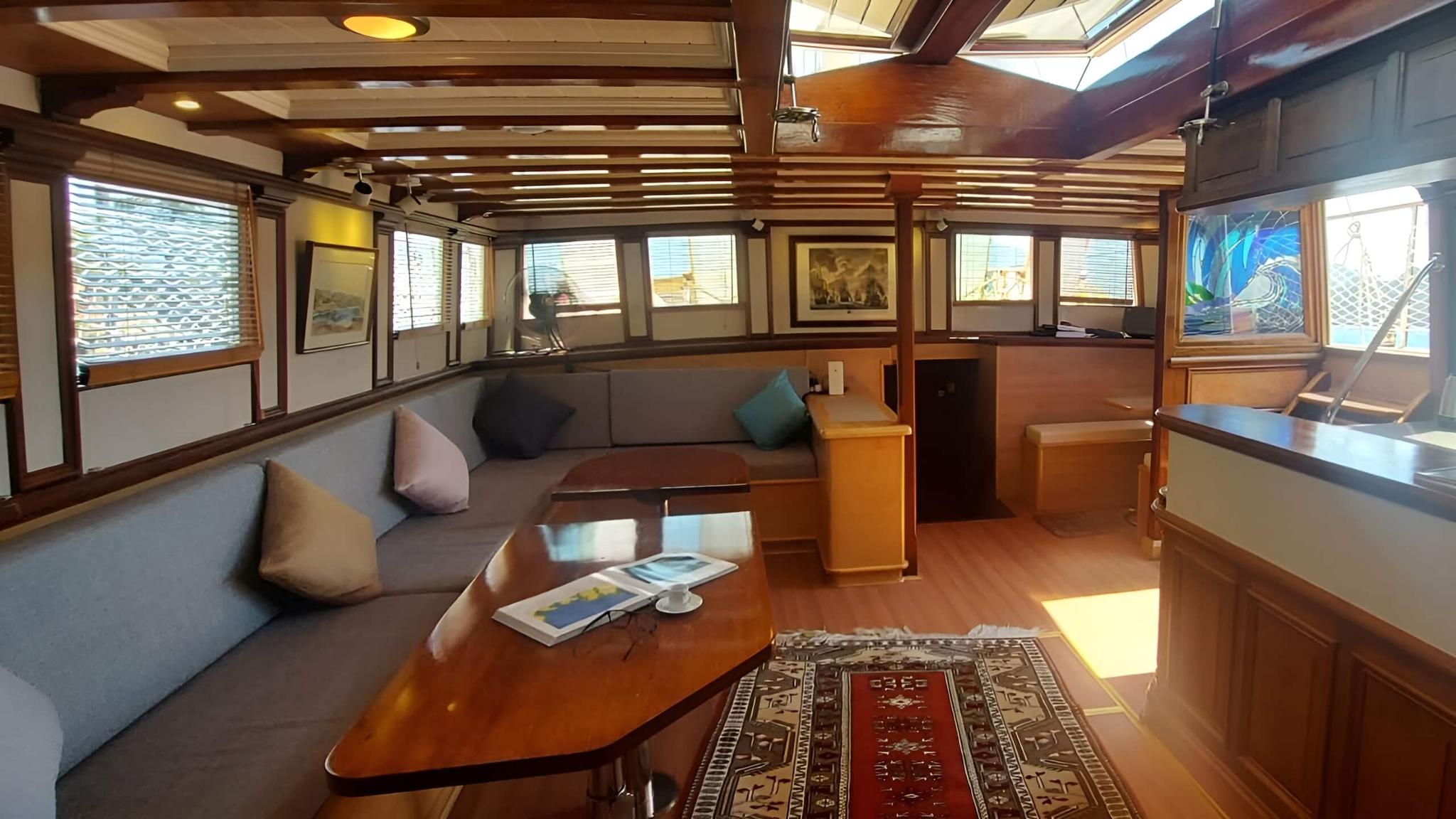 yacht main salon with grey sectional seating, wooden coffee table and traditional rug