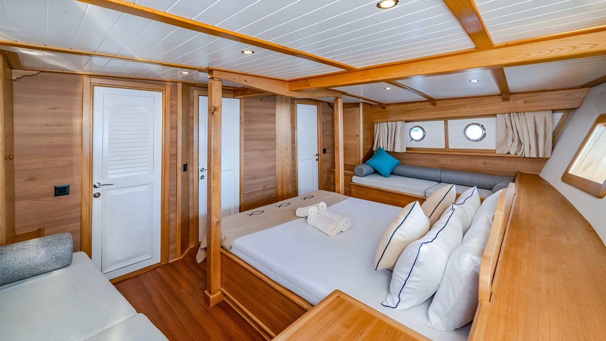 yacht guest cabin with double bed, built-in seating and portholes