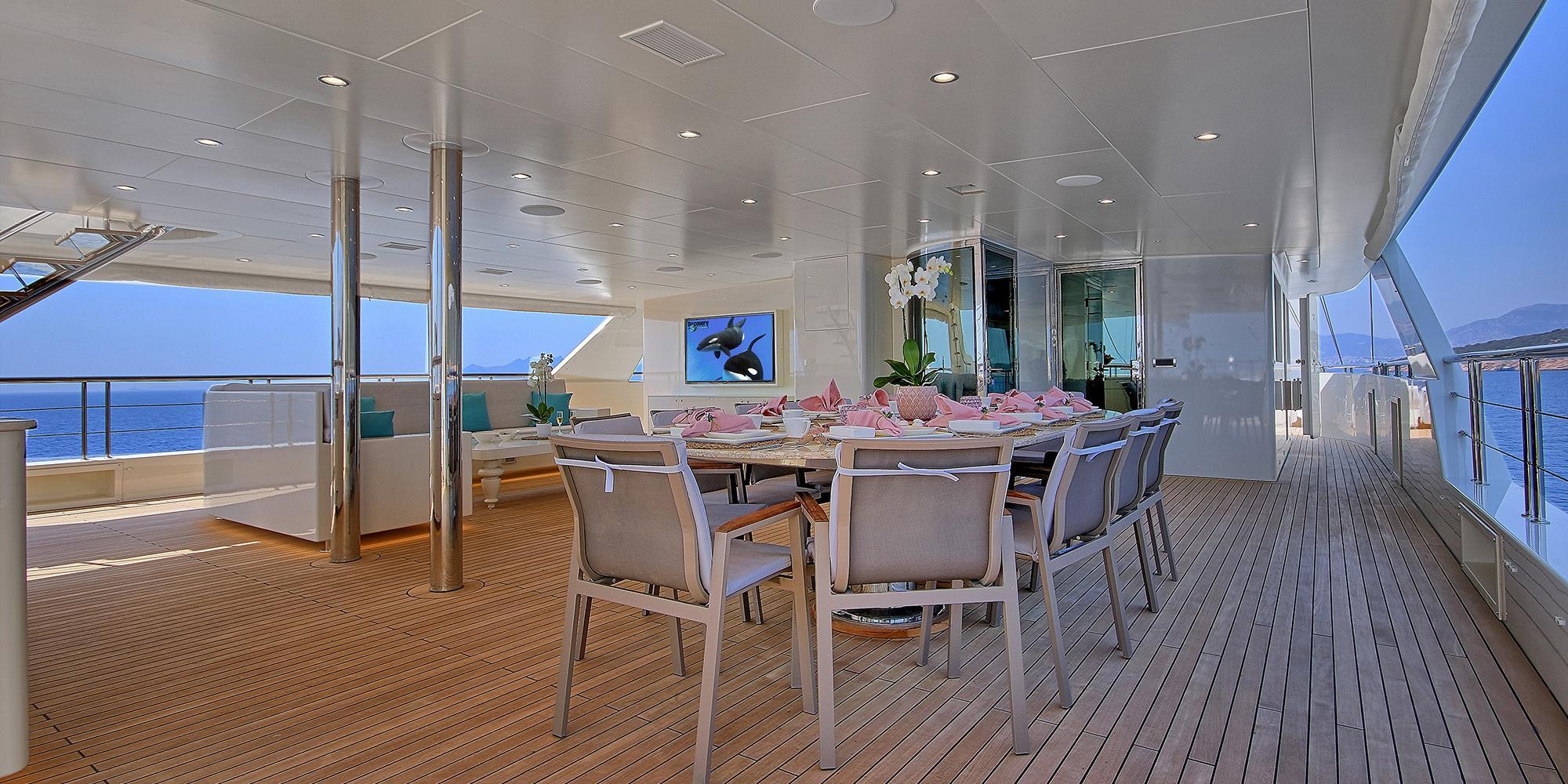 covered aft deck dining area with formal table setting and ocean views on luxury yacht