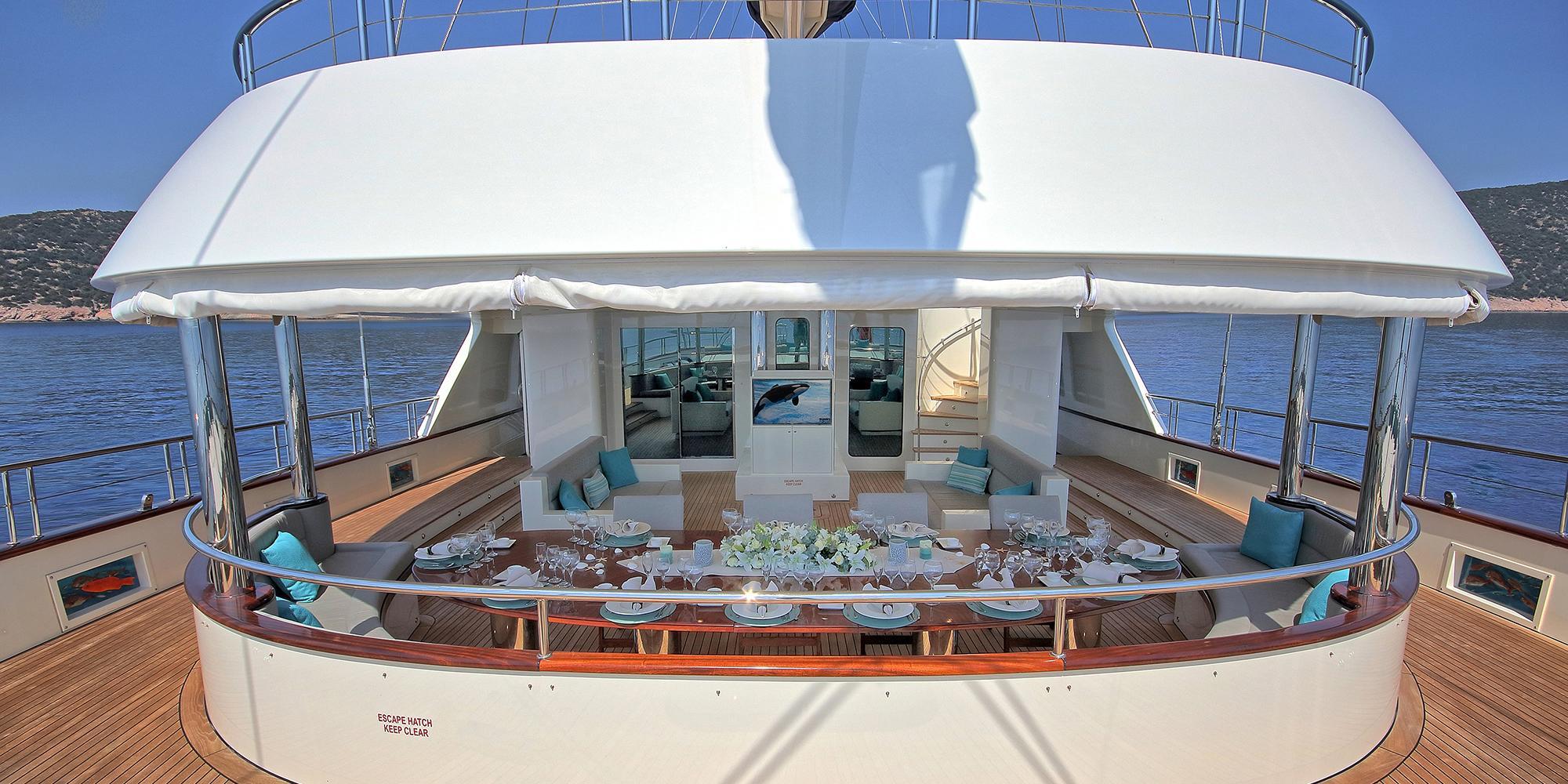 formal dining table set with plates glasses and white floral centerpiece on yacht deck