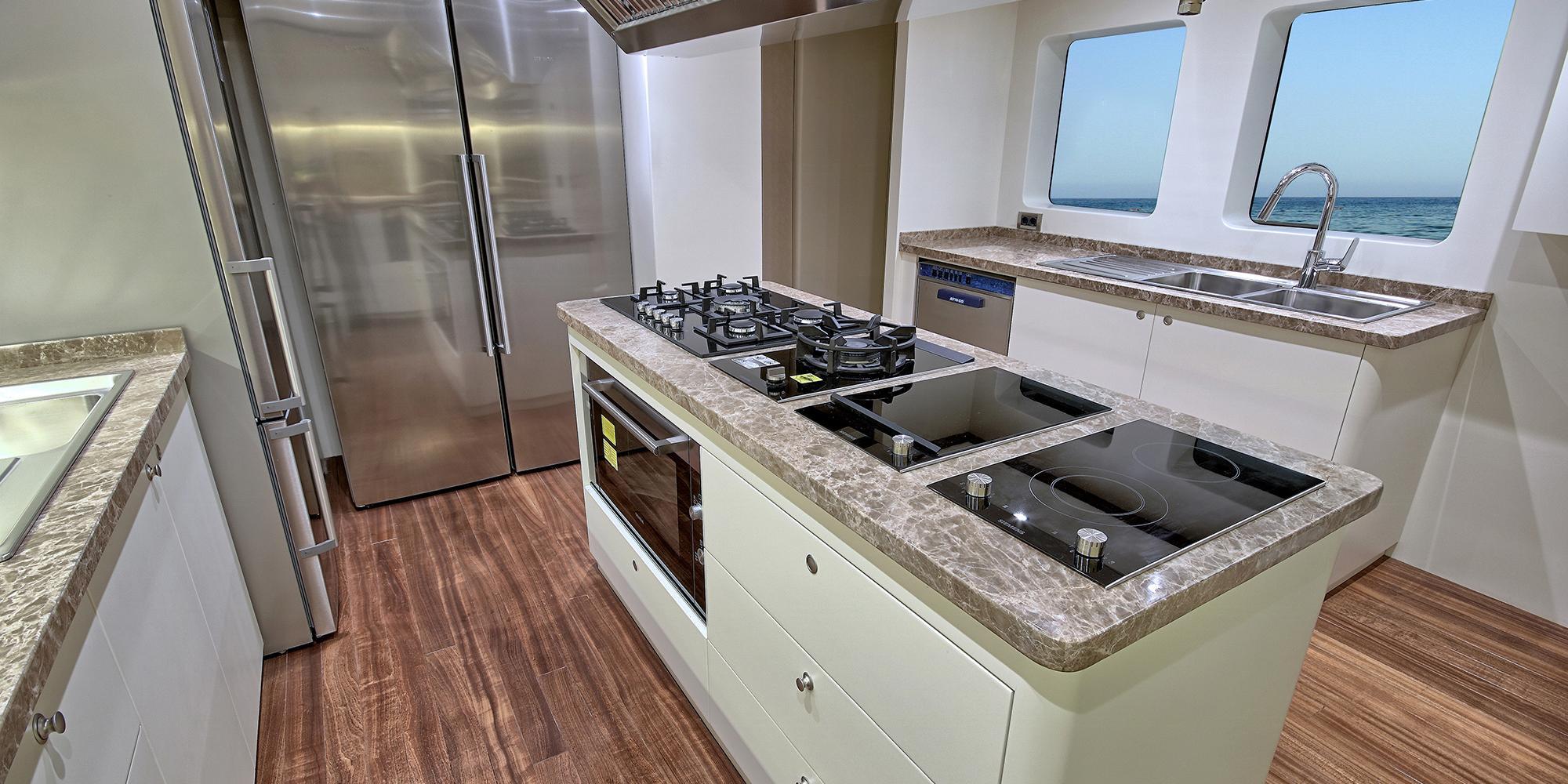 yacht galley with gas cooktop, electric hob, stainless steel appliances and marble countertops
