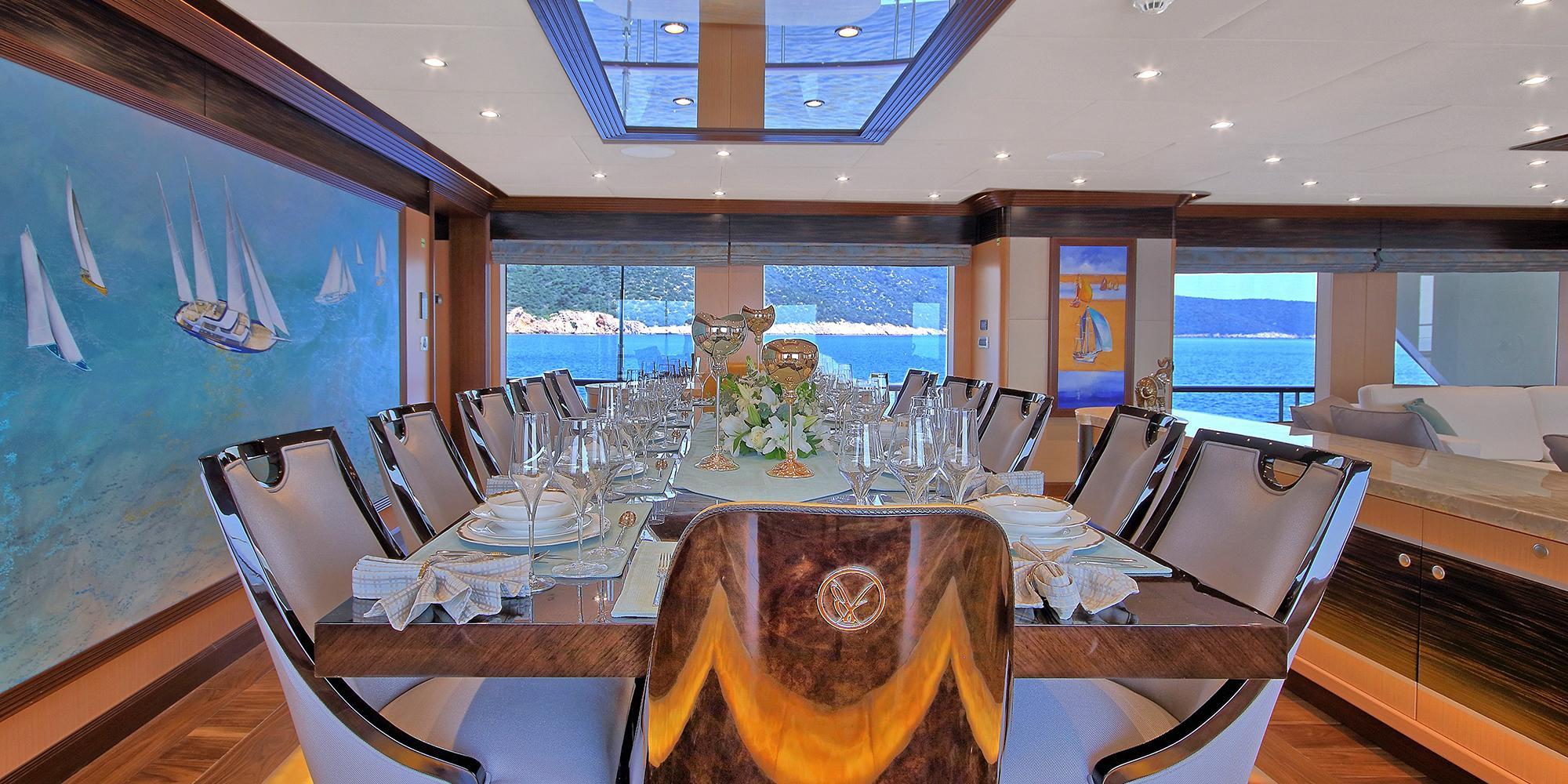luxury yacht formal dining room with crystal glasses, white chairs, and panoramic sea views