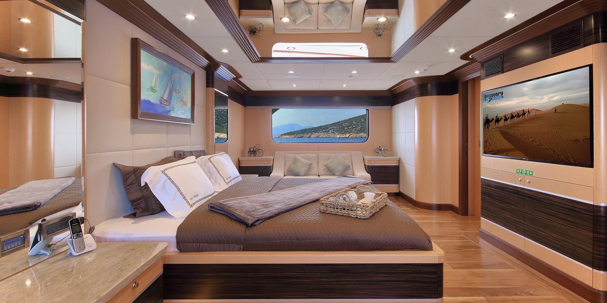 luxury yacht master cabin featuring king bed, panoramic windows, flat screen TV and modern furnishings
