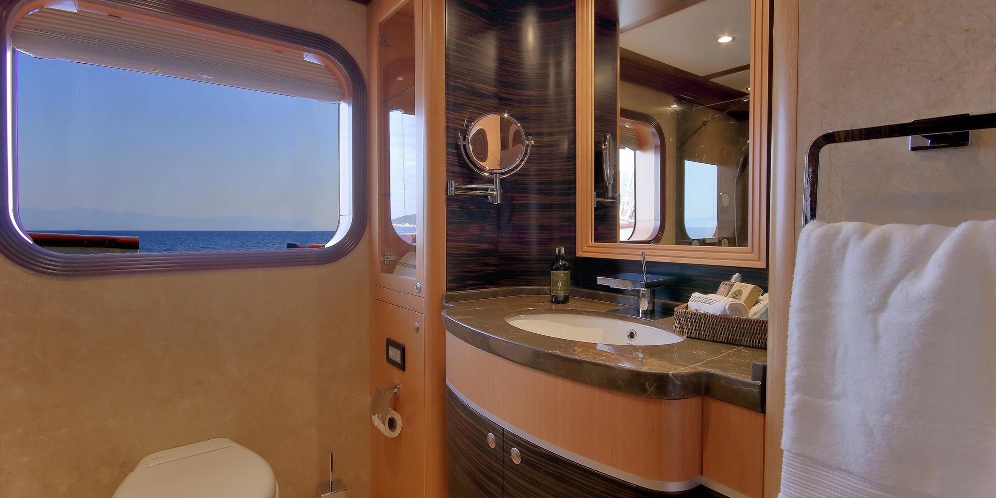 luxury yacht bathroom featuring curved vanity with marble countertop, oval sink, and ocean view porthole