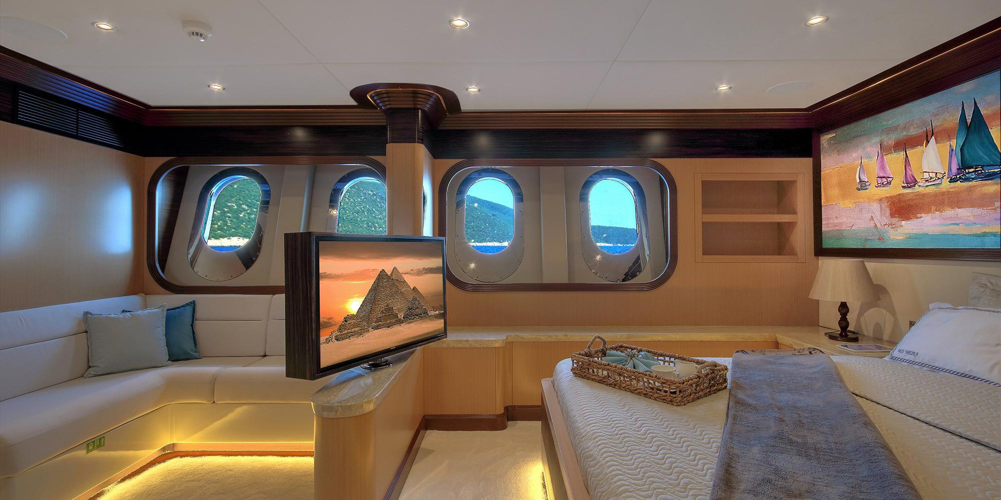 yacht cinema room with large wall-mounted TV screen, white seating and portholes