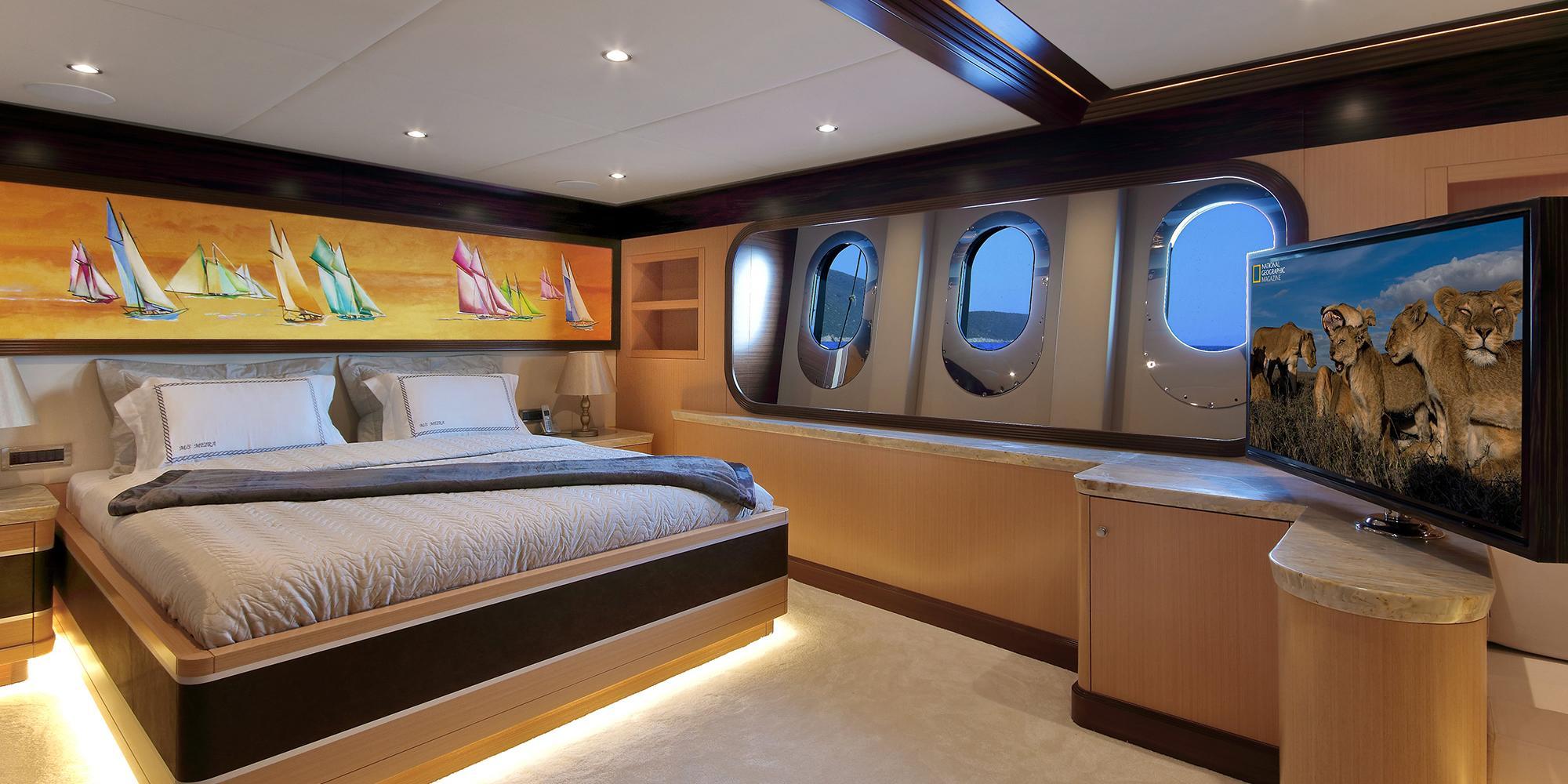 yacht guest cabin featuring double bed, portholes, built-in storage and wall-mounted TV