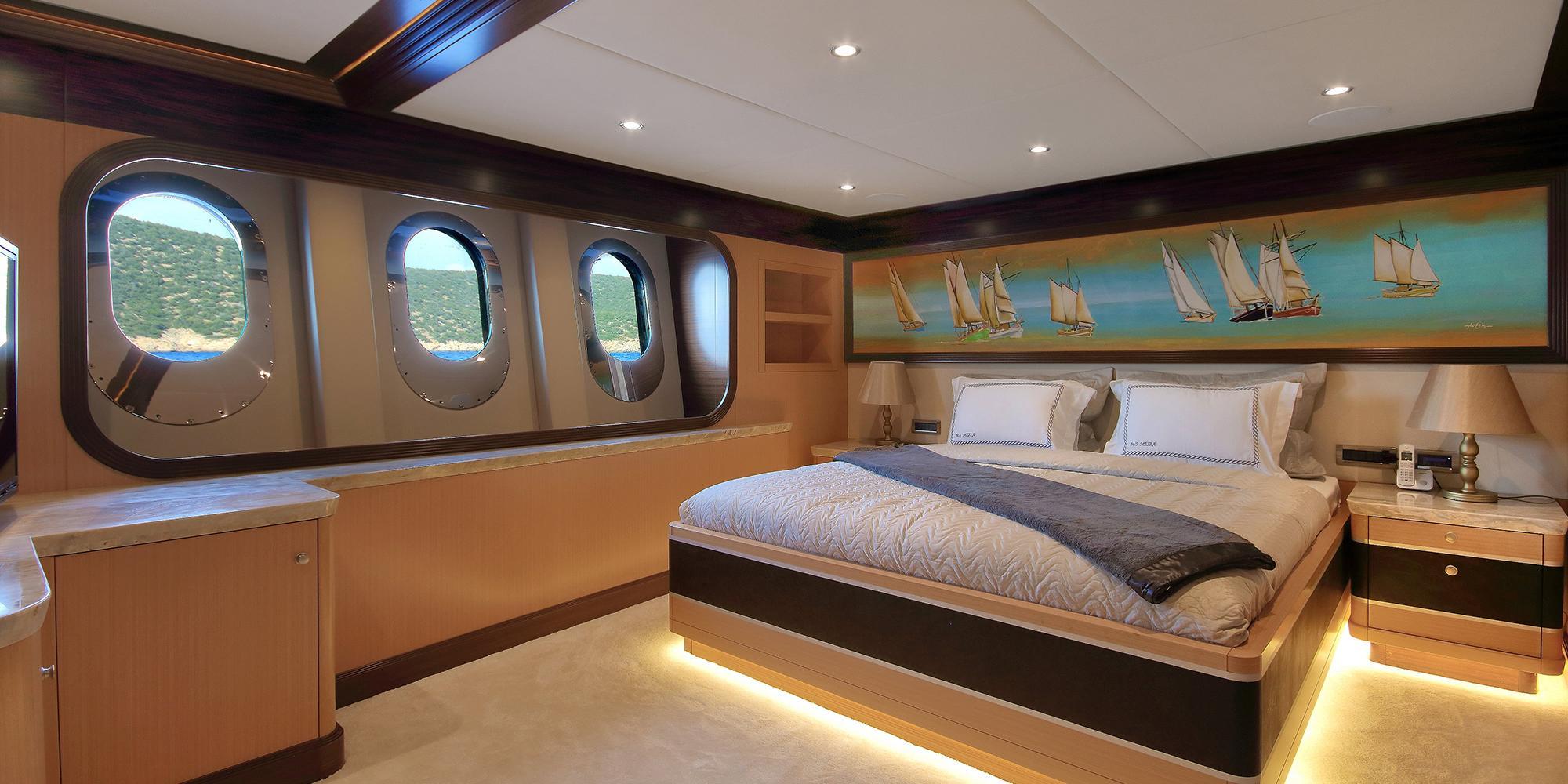 yacht guest cabin featuring double bed with nautical artwork and three oval portholes