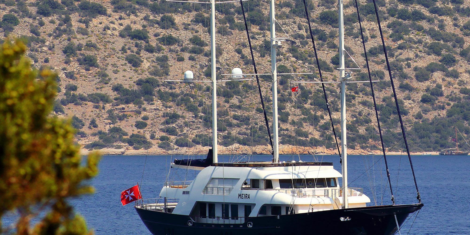luxury gulet MEIRA with dark hull and white superstructure anchored in calm blue bay