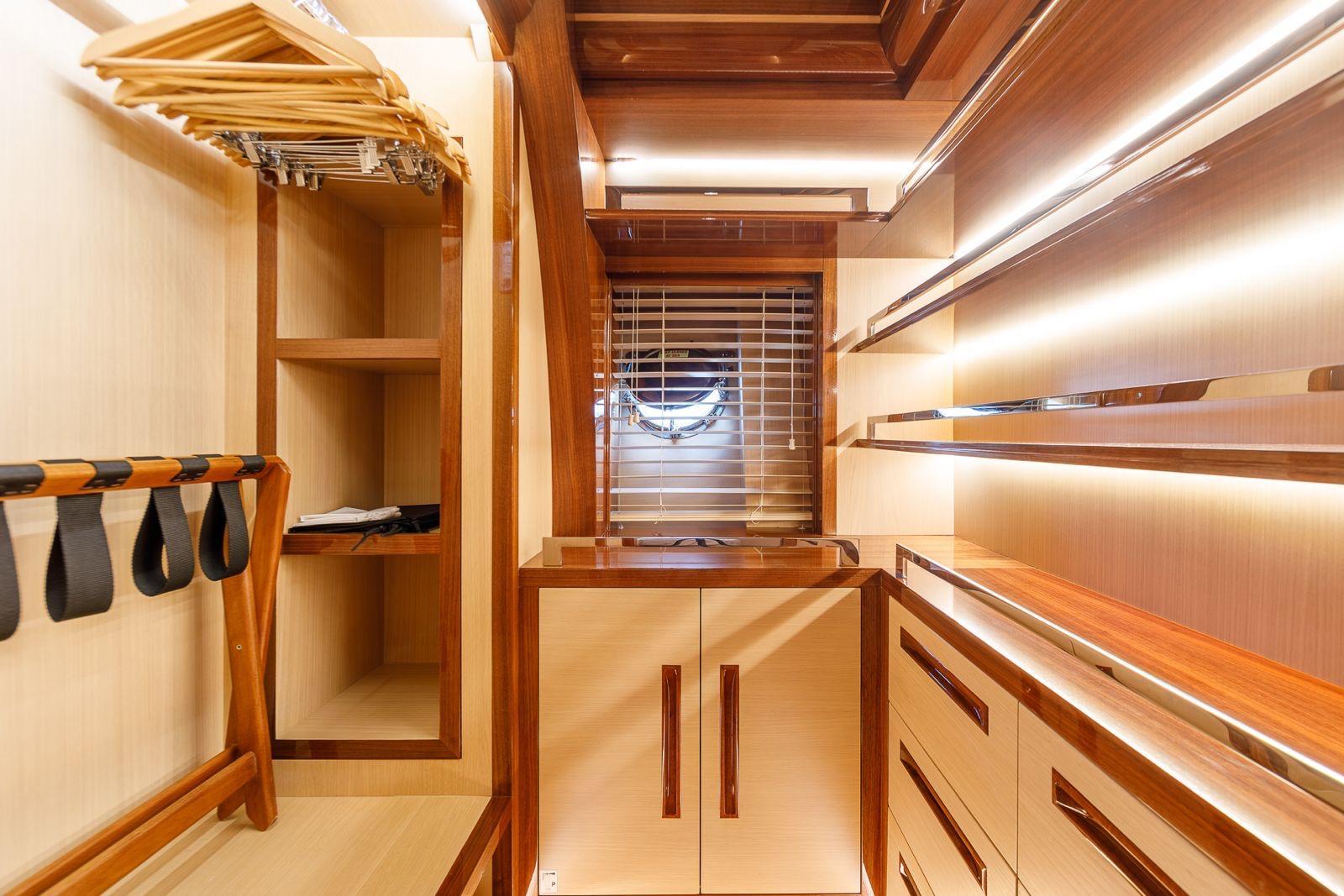 luxury yacht walk-in wardrobe with wooden cabinetry, hanging clothes rails and built-in storage