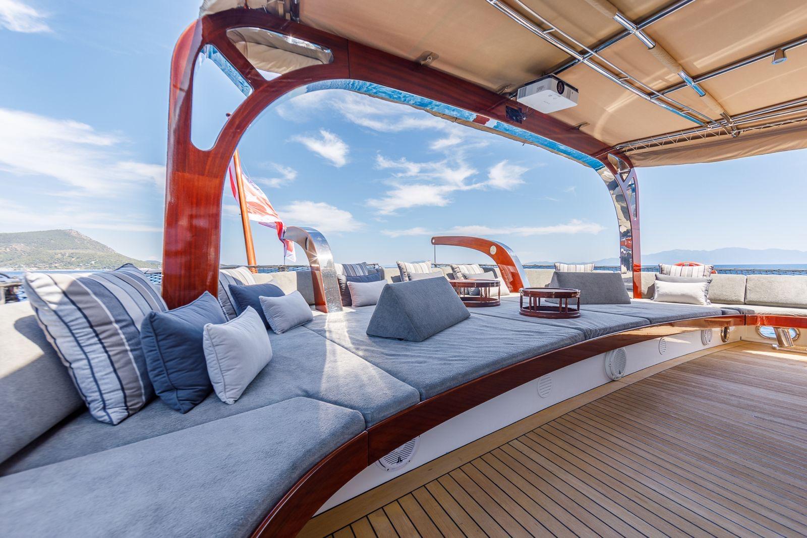 yacht bow seating area with curved blue cushioned benches and teak decking
