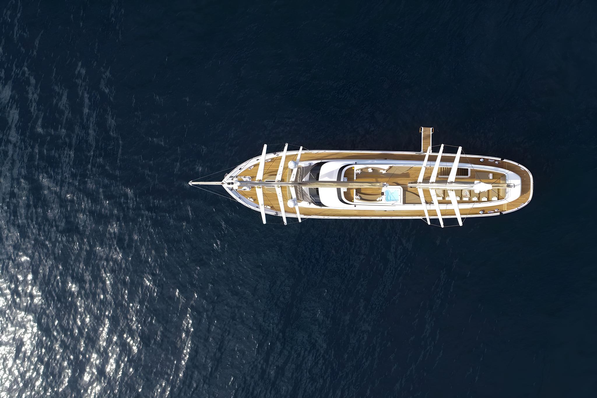 Aerial view of white luxury yacht with teak decking on deep blue water