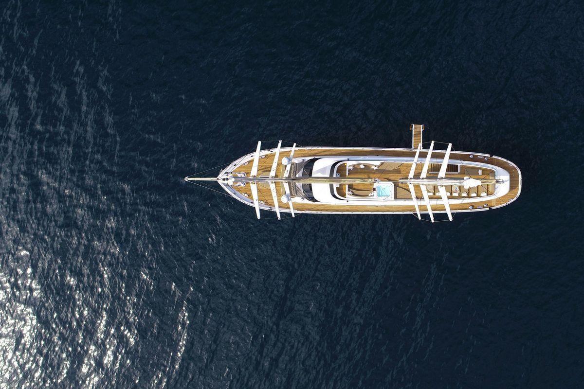 Aerial view of white luxury yacht with teak decking on deep blue water