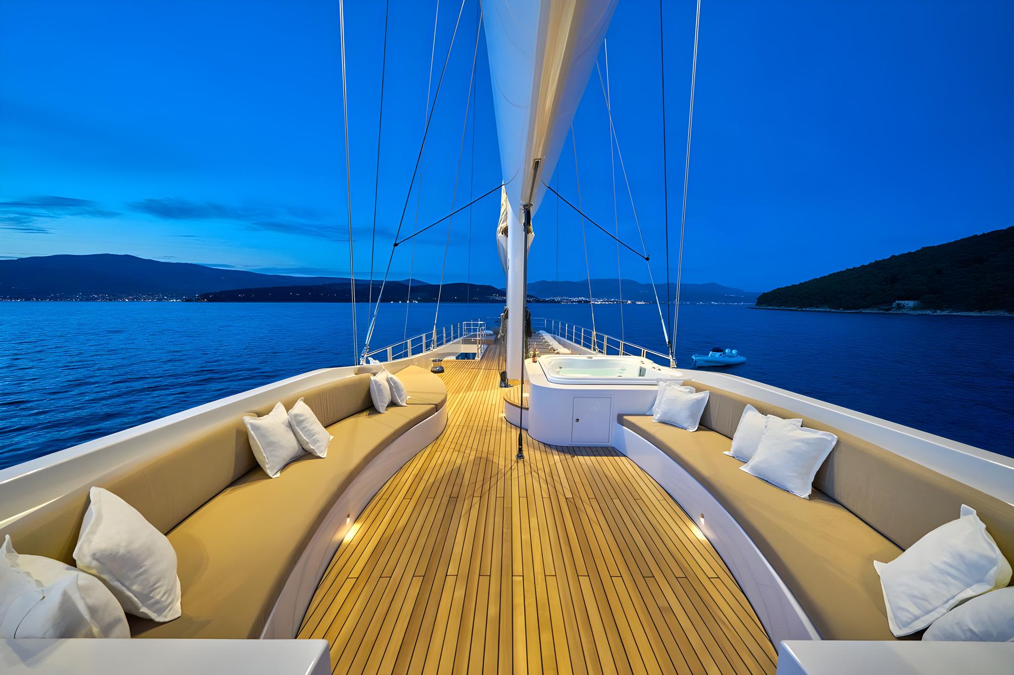 Luxury yacht forward deck with curved seating and teak flooring at dusk