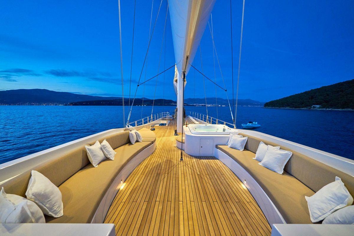 Luxury yacht forward deck with curved seating and teak flooring at dusk