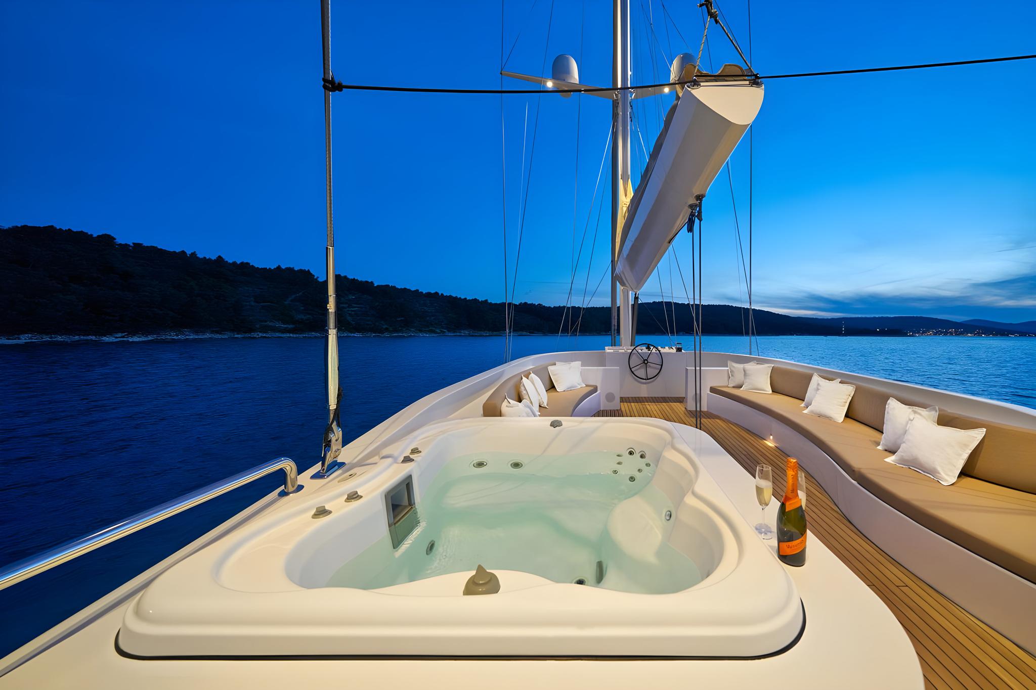 Luxury yacht deck jacuzzi with champagne bottle at sunset anchorage
