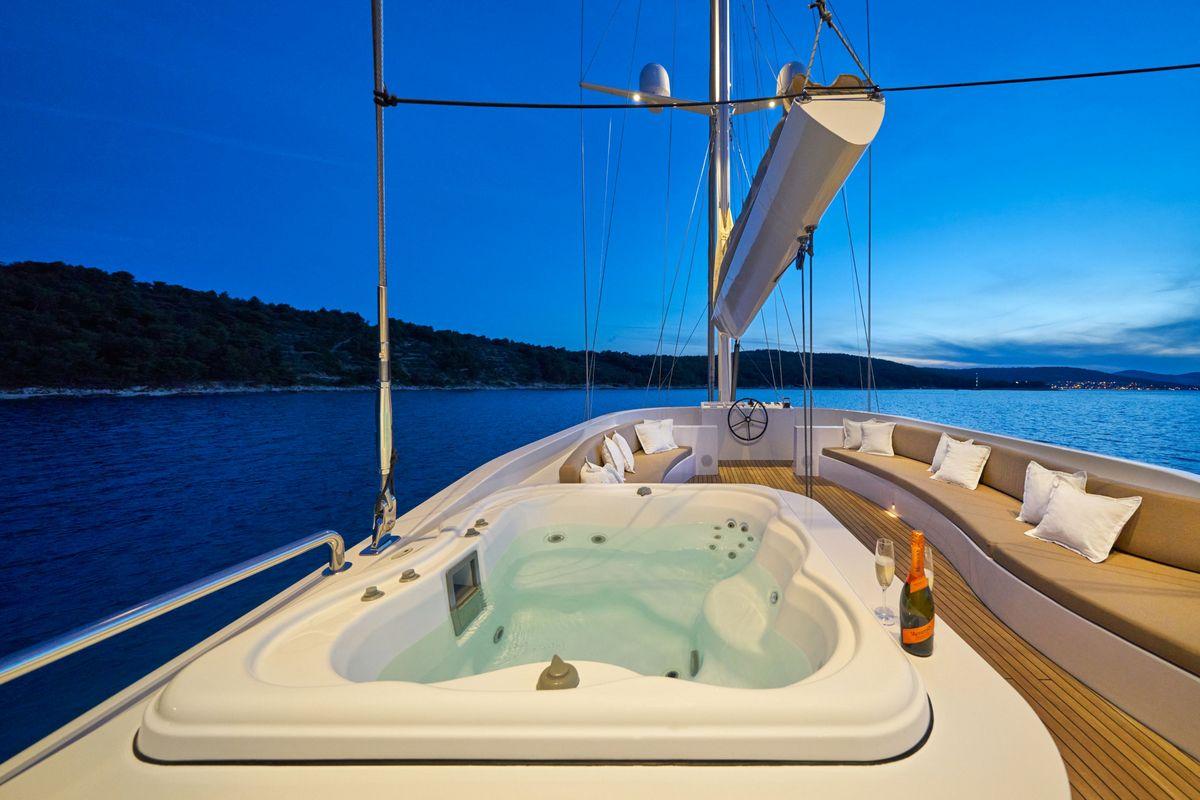 Luxury yacht deck jacuzzi with champagne bottle at sunset anchorage