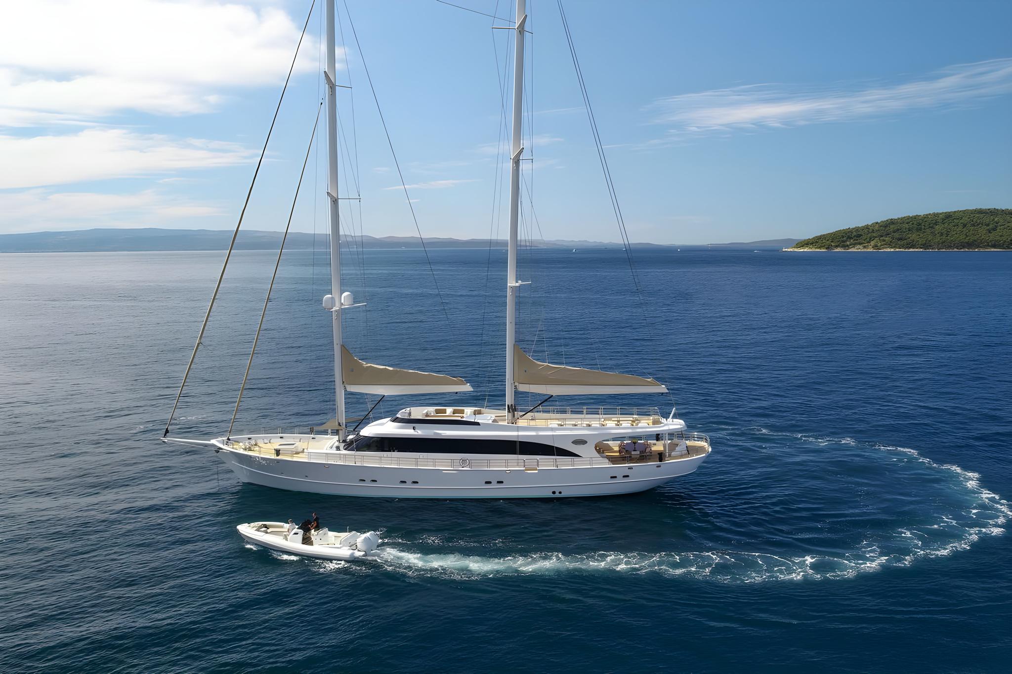 luxury white sailing yacht anchored in blue Mediterranean waters with tender