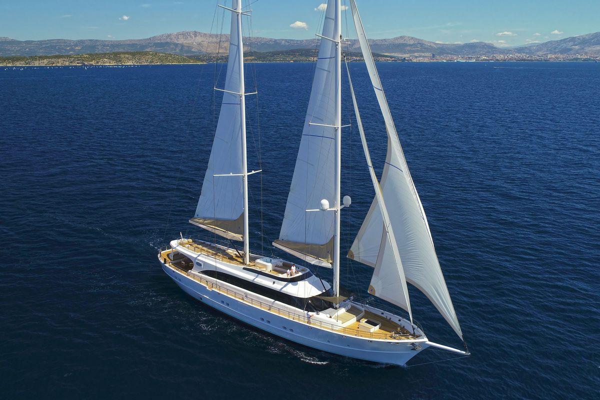 aerial view luxury sailing yacht white hull navy stripe deployed sails