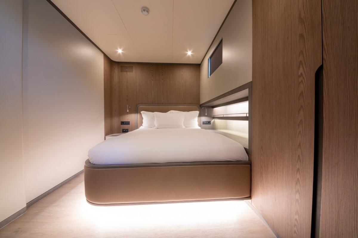 yacht guest cabin featuring double bed with white linens and warm wood paneling