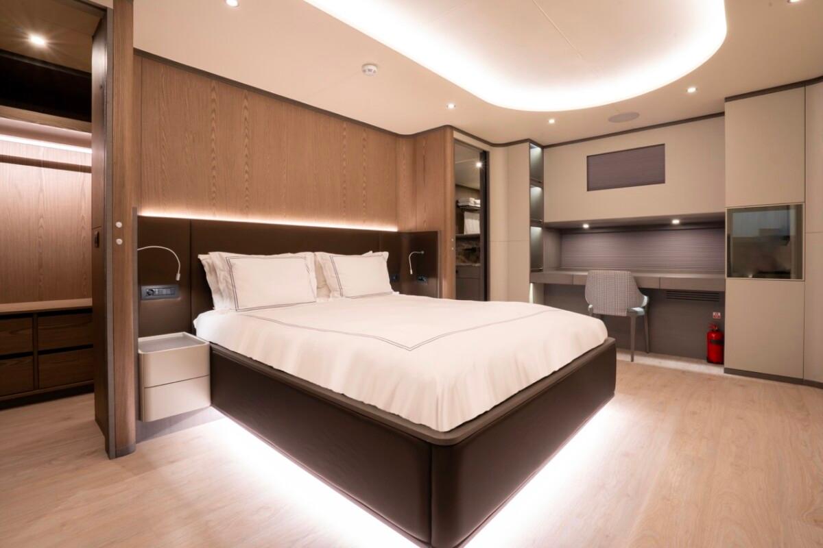 luxury yacht master cabin featuring king bed with white linens and built-in desk area