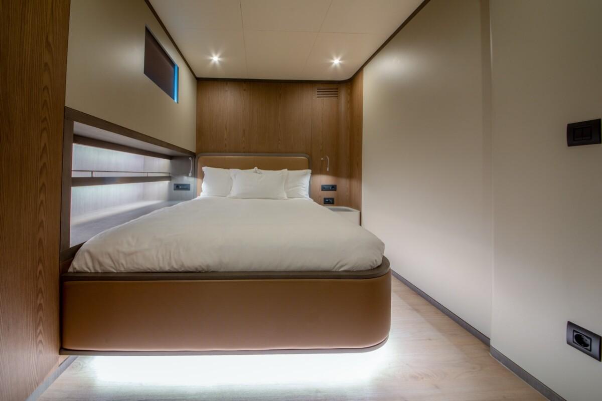 yacht guest cabin featuring double bed with white linens and contemporary wood paneling
