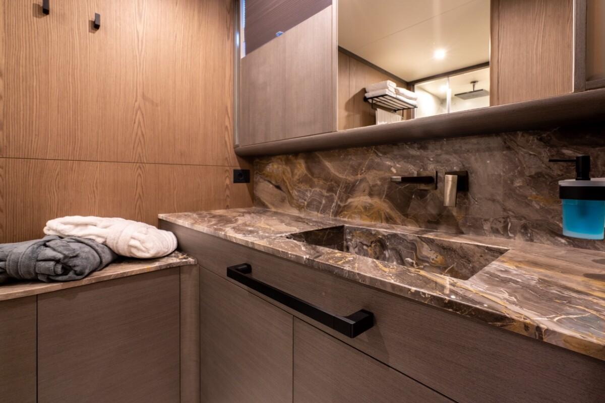 luxury yacht bathroom vanity with dark marble countertop, integrated basin, and wood cabinetry