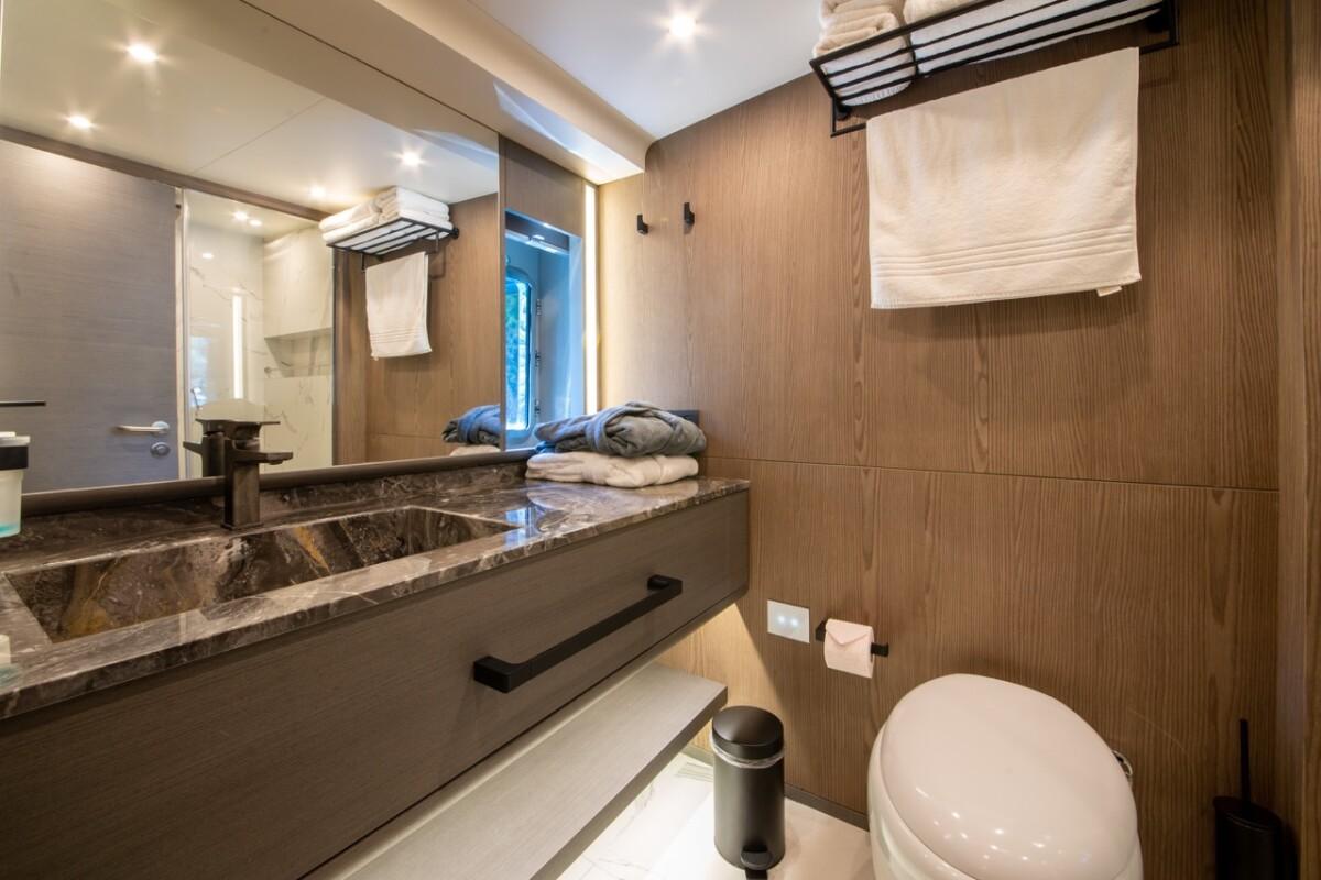 modern yacht guest bathroom featuring dark marble vanity countertop with integrated sink and warm wood wall paneling